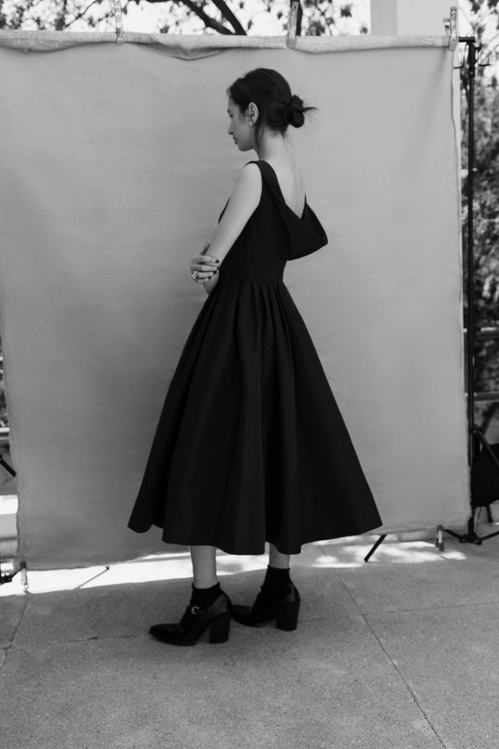 Pitahaya dress in Black — faille fabric, cowl back detail, full skirt above-ankle length, self-lined bodice, fully silk-lined skirt, hidden pockets, concealed side zip, side profile view