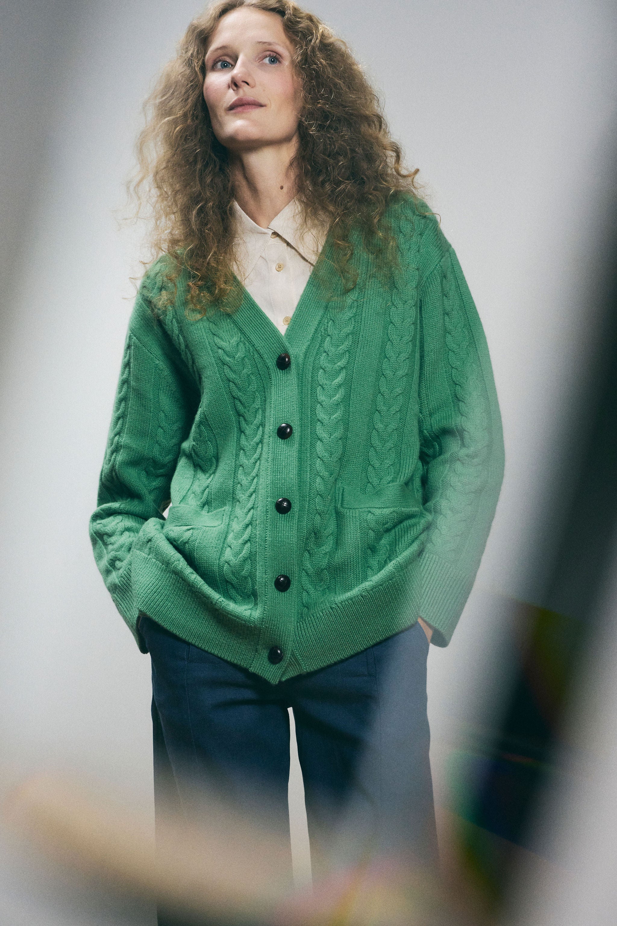 Sanmiguelito cardigan in Green — 100% Extrafine Merino wool, horseshoe cable and rib knit pattern, dropped shoulder, ribbed cuffs and hem, dark brown leather buttons, below-waist length, full-length front view