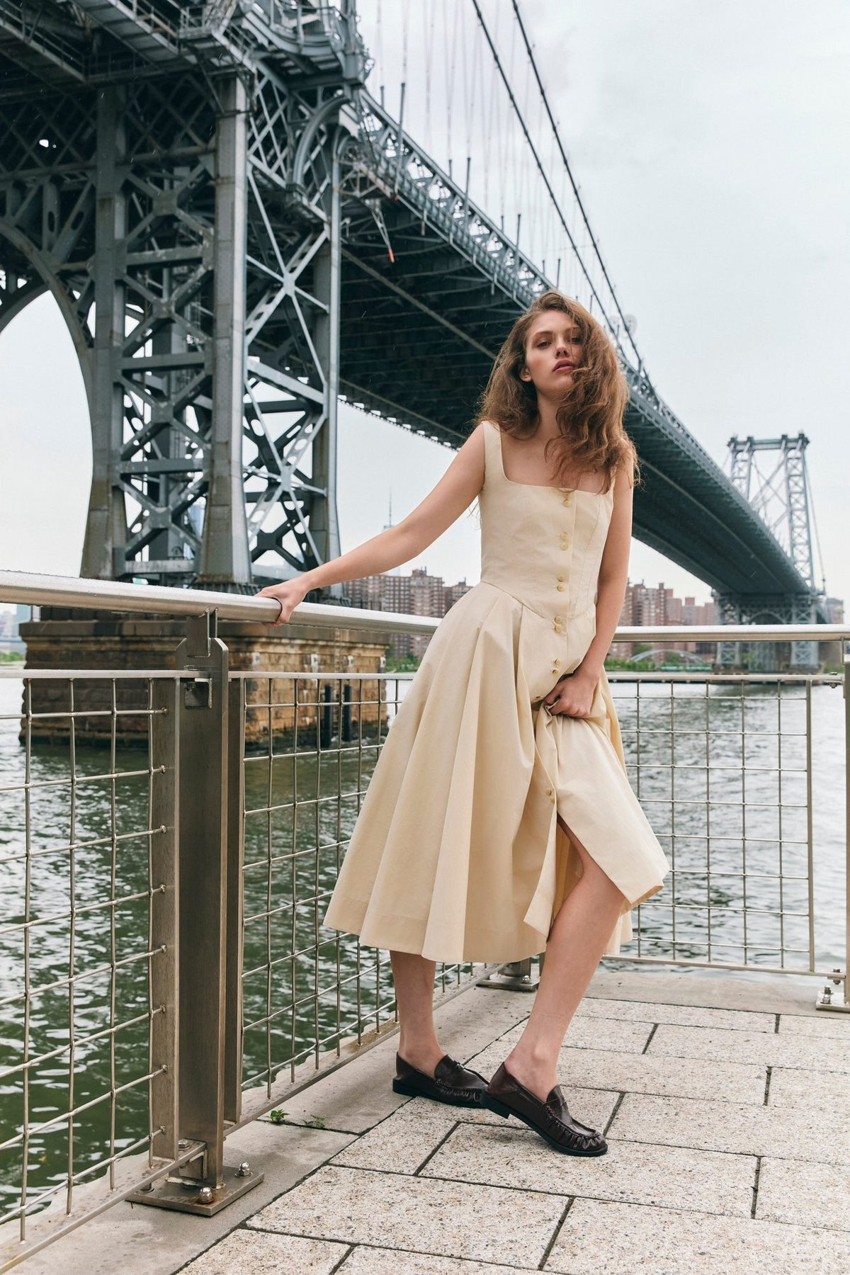 Woman wearing the Stathe Toloache Dress in Powder by the Williamsburg Bridge, New York — editorial