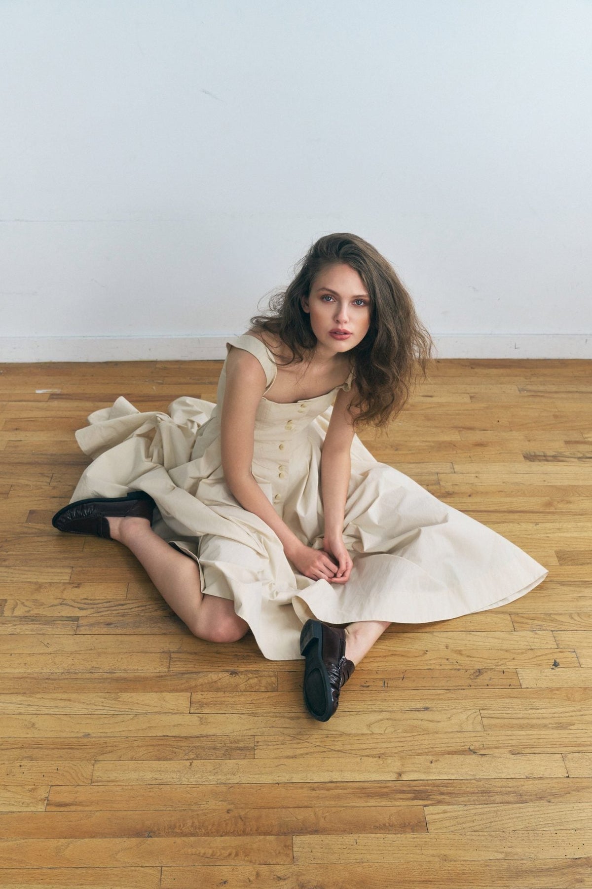 Woman wearing the Stathe Toloache Dress in Powder, seated — editorial